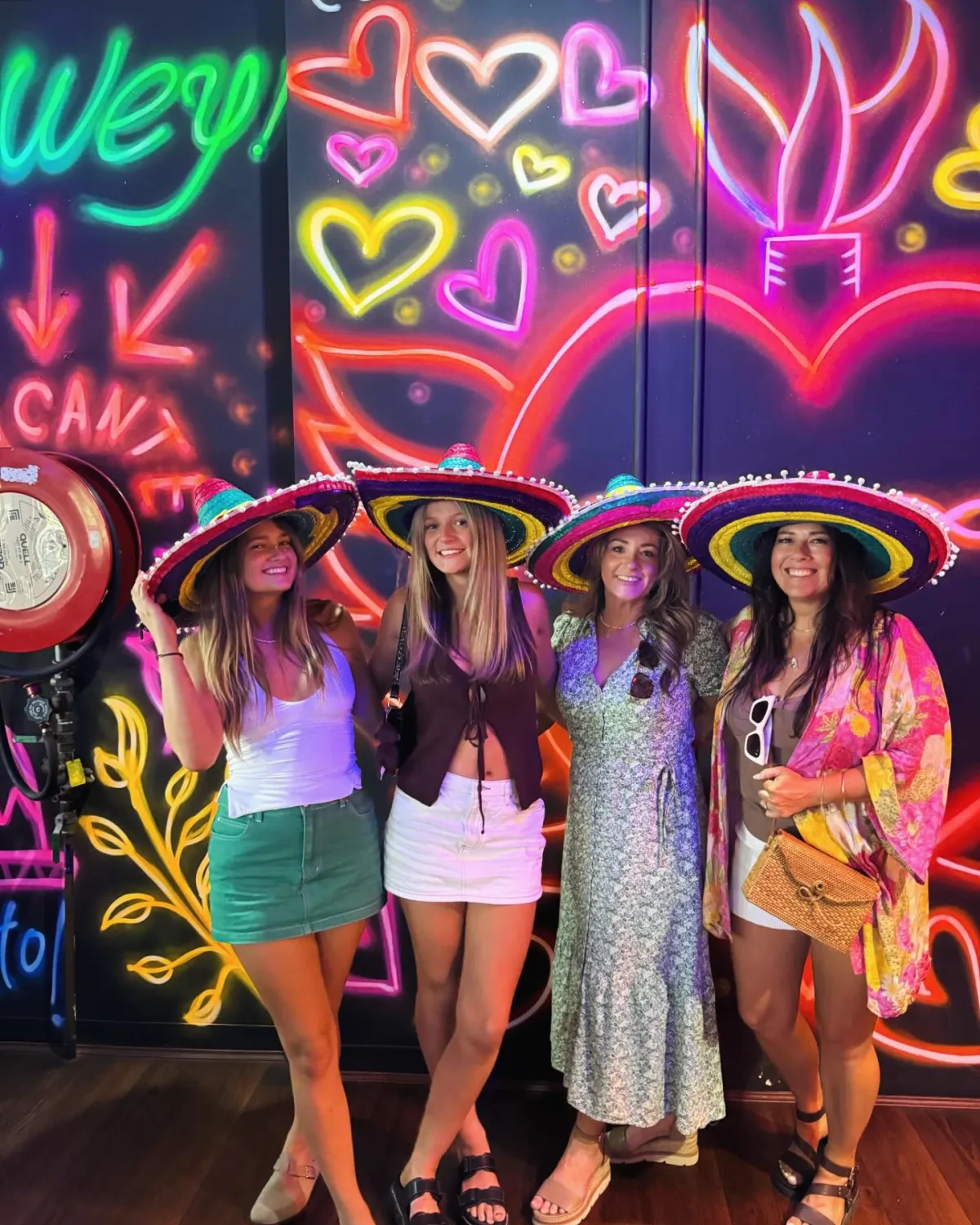 Friends posing at El Mexicano neon mural