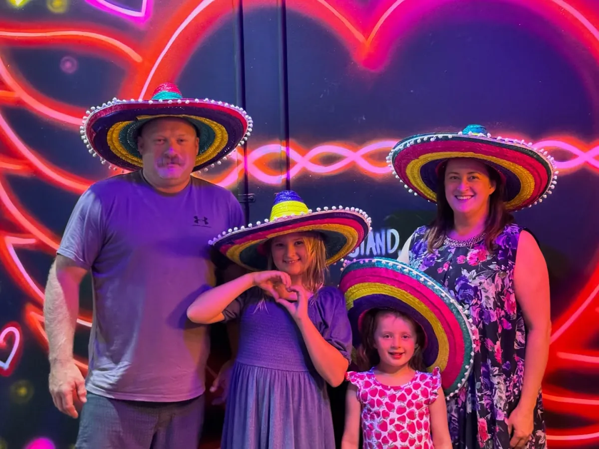 Family fiesta in front of neon heart wall