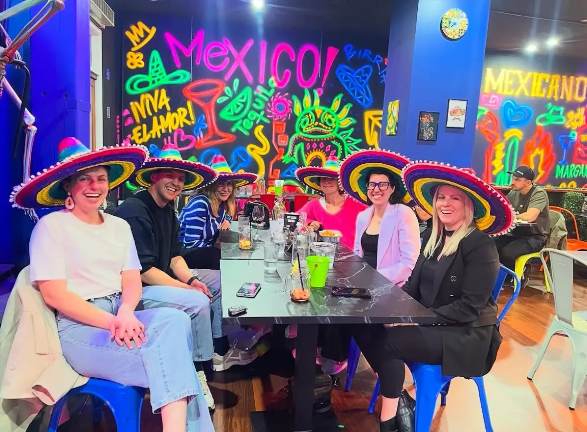 Group dinner under Mexico neon graffiti